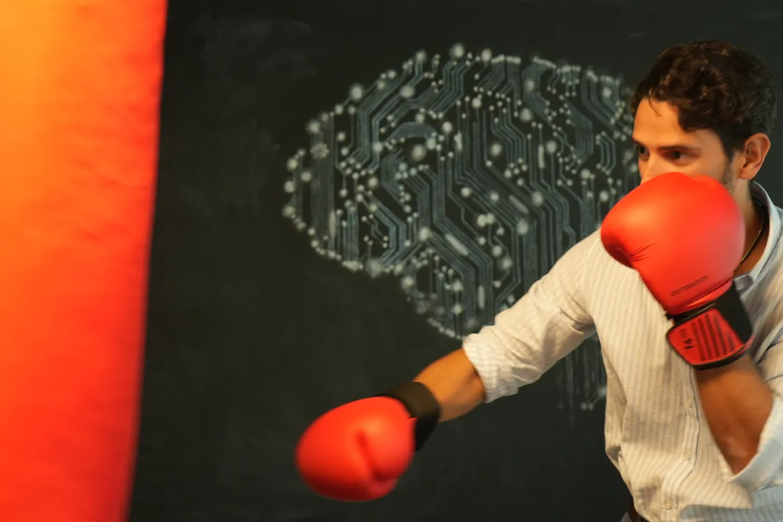 A team member with boxing gloves in front of a circuit board wall