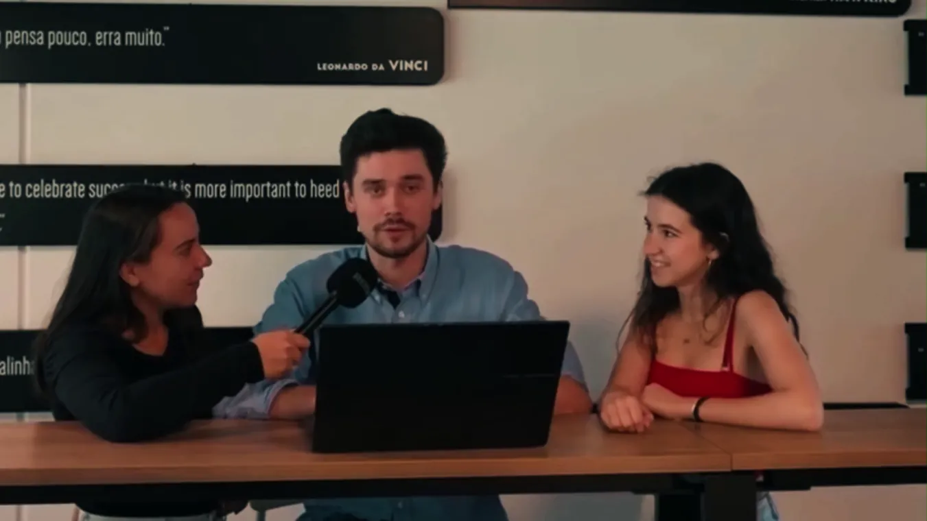 Three team members recording a conversation around a laptop